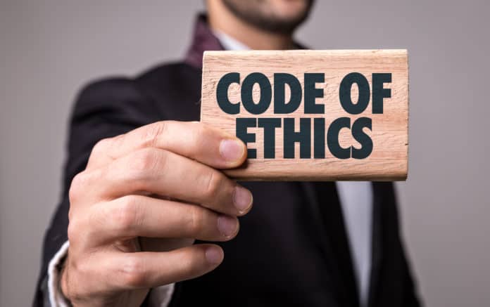 uomo che mostra una targa di legno con la scritta code of ethics